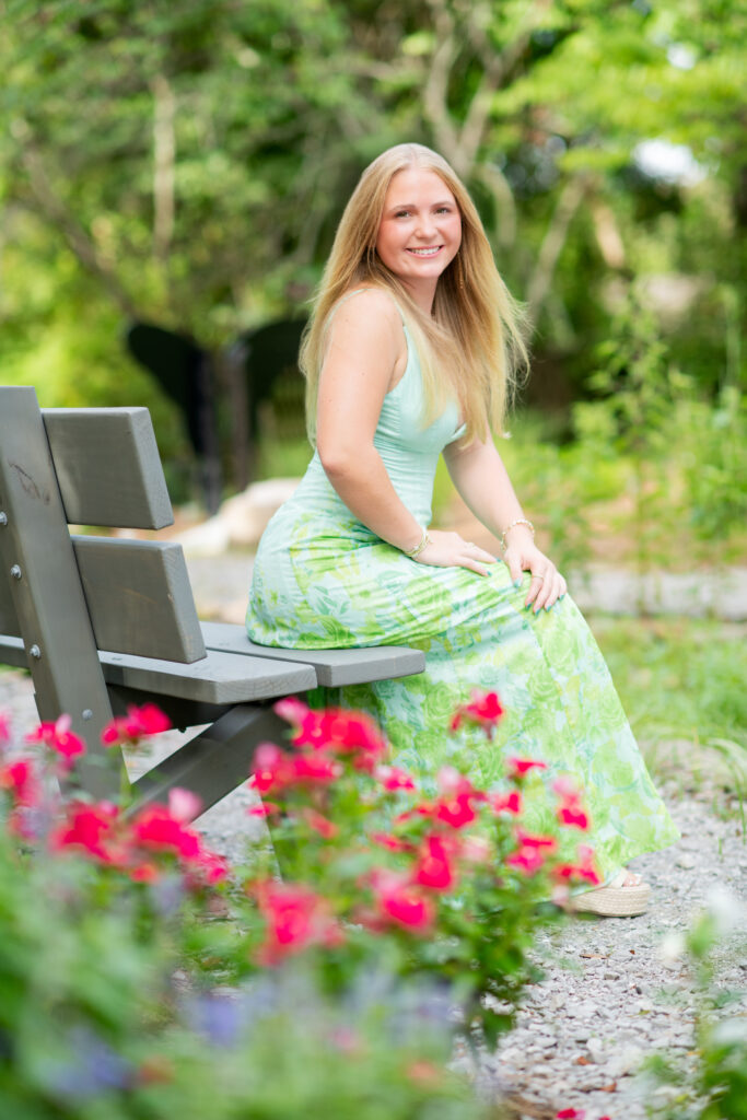 Senior girl in sundress sitting on bench in Strawberry Patch Park Madison, MS