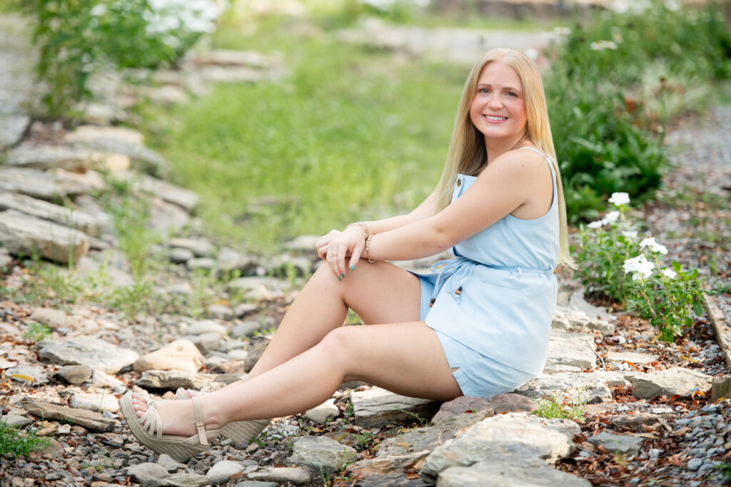 Senior girl sitting on a rock in Strawberry Patch Park in Madison, MS