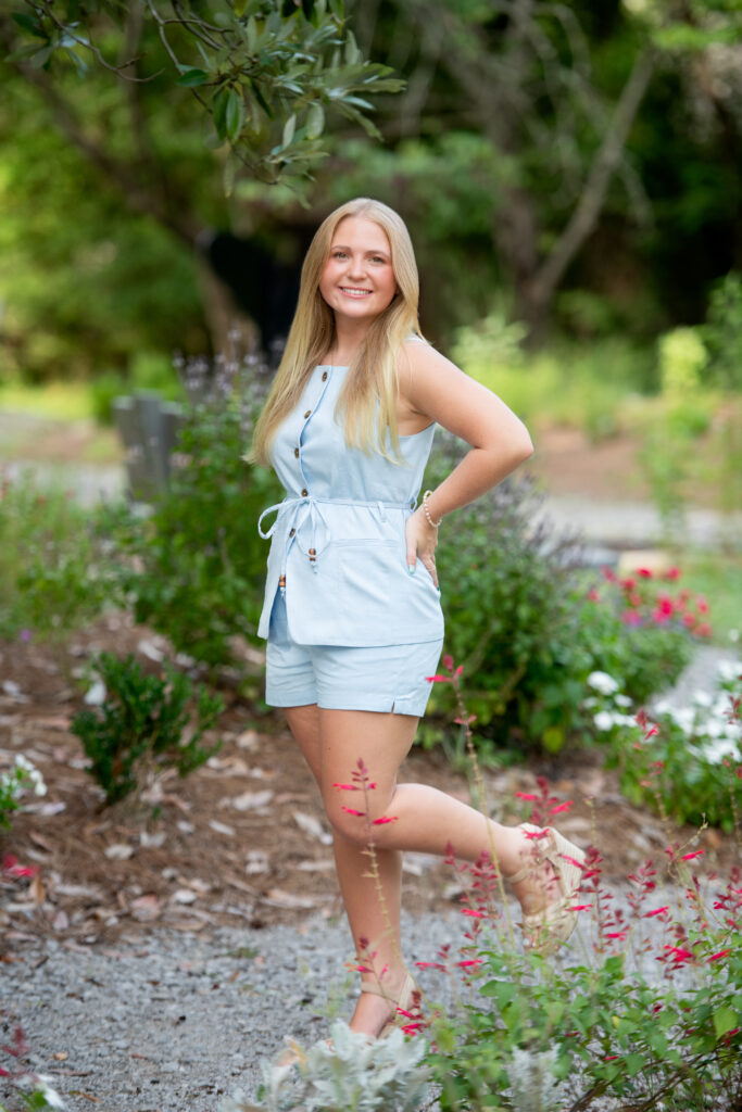 Senior girl standing on rock path in Strawberry Patch Park flower garden in Madison, MS