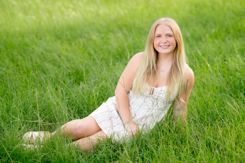 Senior girl sitting in field in Madison, MS